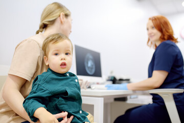 Toddler boy with his mom are at appointment with a pediatric neurologist. A mother tells an attentive doctor about her baby’s injury.