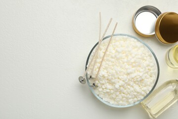 Soy wax and other supplies for making candles on white table, flat lay. Space for text