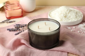 Soy wax candle, pink napkin and lavender flowers on table