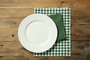 Napkins and empty plate on wooden table, top view