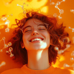 A young woman with curly hair and glasses smiles brightly against a vibrant orange background