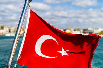  Turkish flag waving proudly on a boat, Istanbul skyline in the background. Beautiful sunny day on the Bosphorus Strait. Perfect for travel, tourism, and cultural imagery.