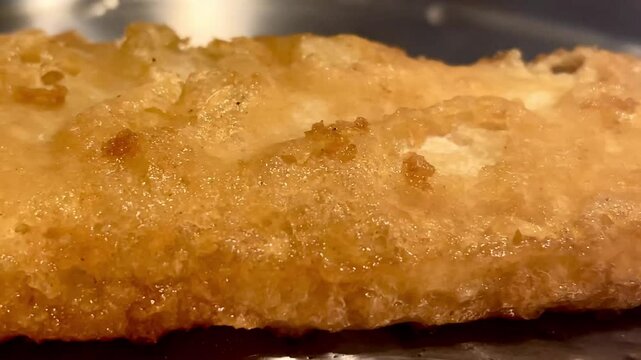 Crisp golden battered fish sizzling gently, embodying the essence of a traditional and comforting British dish, English fish and chips