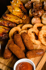 Assorted grilled meat appetizers on wooden board, top view.