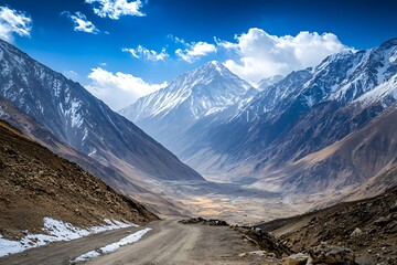 A high mountain pass with panoramic views of surrounding peaks, covered in snow and under a blue sky.