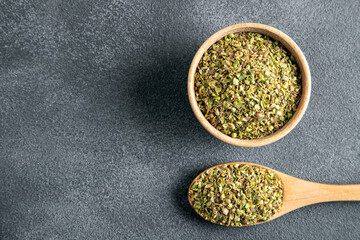 A bowl full of dried and ground natural mountain thyme on gray background.
