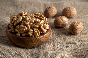 Peel walnuts and whole walnuts in wooden bowl,closeup
