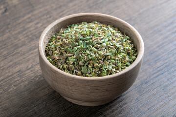 A bowl full of dried and ground organic mountain thyme on wooden table