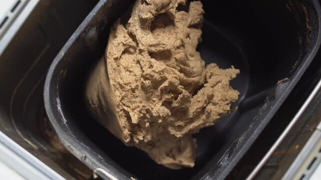 Black bread maker filled with light-brown dough.