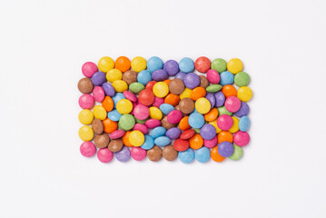 Brightly coloured sweets on white background. Rainbow colored candy. Happiness and cheerfulness concept, top view