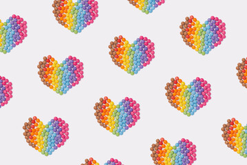 Brightly coloured sweets form a heart shape on white background. Rainbow colored candy. Happiness and cheerfulness concept