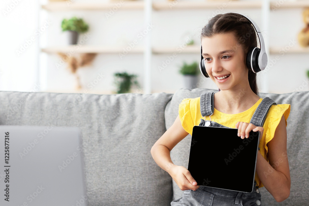 Aufkleber Distance Education. Smiling girl having video call with teacher, holding digital tablet with blank empty screen showing done task result using laptop. Child studying remotely
