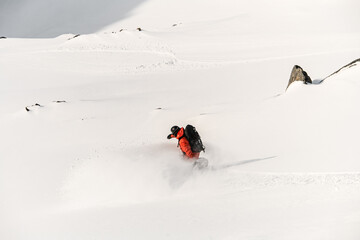 Top view of a skier in an orange jacket going down on a splitboard