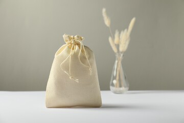 Beige burlap sack on white surface against gray background