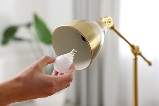 Man changing light bulb in lamp at home, closeup