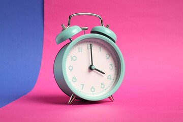 One turquoise alarm clock on color background