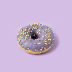 Purple glazed donut on pastel background. Creative food concept.
