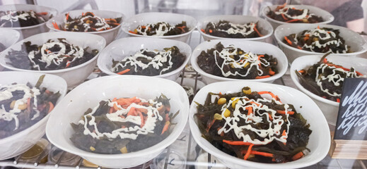 Freshly prepared salad bowls with colorful vegetables and creamy dressing on display