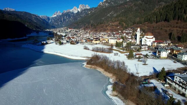 Aerial 4K Drone 3-Shot Sequence of Auronzo di Cadore in Winter: Snowy Townscape, Close-up of Historic Church and Frozen Lake Santa Caterina near Cortina 2026 Winter Olympics Venue, Dolomites Italy