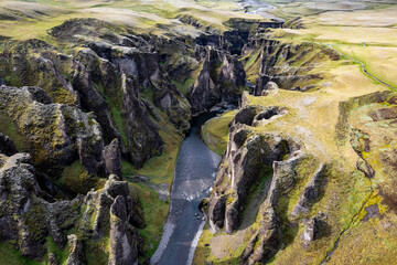 Breathtaking aerial drone view of a serene river winding through a majestic Fjadrargljufur Canyon in Iceland