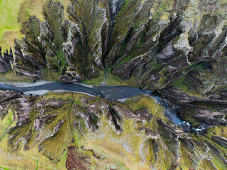 Breathtaking aerial drone view of a serene river winding through a majestic Fjadrargljufur Canyon in Iceland