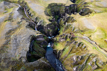 Breathtaking aerial drone view of a serene river winding through a majestic Fjadrargljufur Canyon in Iceland