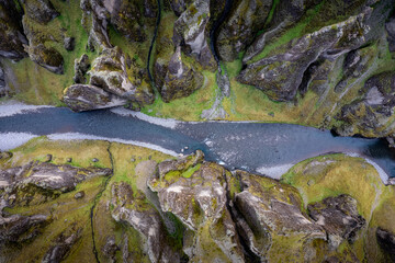Breathtaking aerial drone view of a serene river winding through a majestic Fjadrargljufur Canyon in Iceland