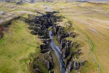 Breathtaking aerial drone view of a serene river winding through a majestic Fjadrargljufur Canyon in Iceland