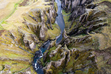 Breathtaking aerial drone view of a serene river winding through a majestic Fjadrargljufur Canyon in Iceland