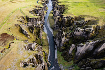 Breathtaking aerial drone view of a serene river winding through a majestic Fjadrargljufur Canyon in Iceland