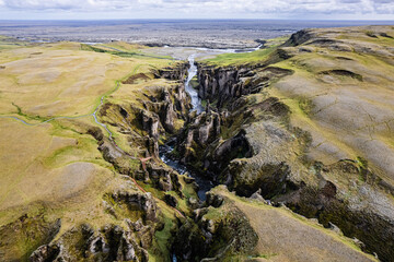 Breathtaking aerial drone view of a serene river winding through a majestic Fjadrargljufur Canyon in Iceland