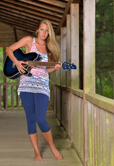 Sexy young woman on a wooden porch with guitar