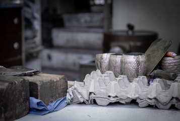Artisan crafting ornate silver cups in traditional workshop