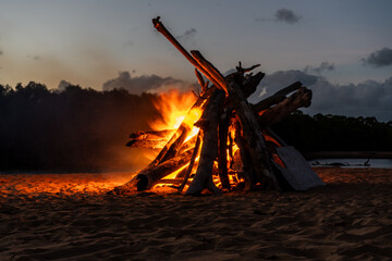 A large bonfire on the beach at sunset