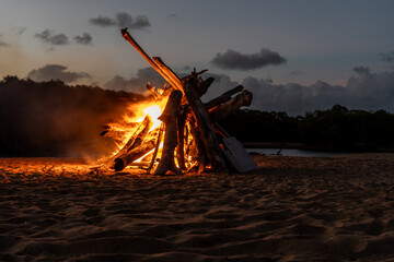 A large bonfire on the beach at sunset