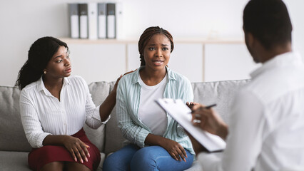 Black male psychologist consulting millennial LGBT couple at clinic, panorama. Psychotherapist having session with young homosexual family at office. Marriage counseling concept
