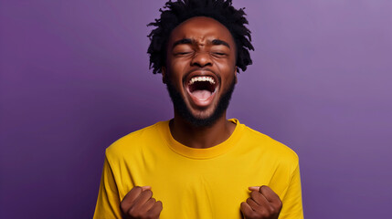 Joyful young man celebrating with fists raised against a purple background