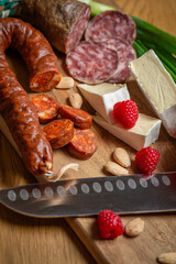 Bright sliced sausages and cheeses with vegetables and herbs lie on a board