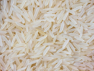 Close-up shot of dry, uncooked long grain basmati rice. Grains are slender and translucent, natural texture.