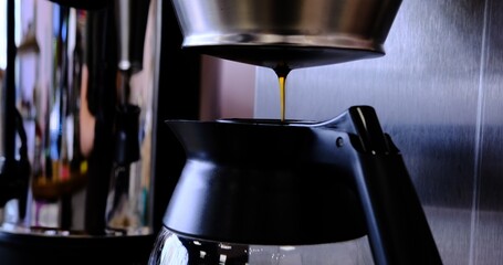 Freshly brewed coffee filters into sleek decanter from professional coffee machine showcasing rich...