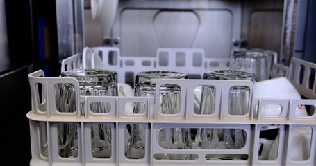 A dishwasher in black gloves removes a clean plate from the dishwasher highlighting hygiene and...