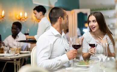 Excited girl telling her boyfriend story sitting in the restaurant