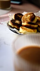 A woman forks fluffy golden pancakes with crispy edges while coffee is in the background out of focus breakfast concept morning meal with pancakes coffee and fork casual dining brunch at home