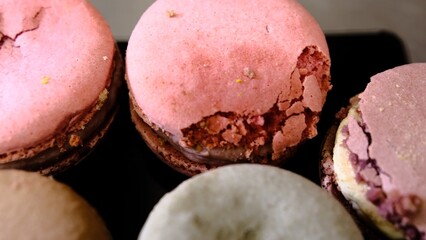 Damaged colorful macarons in close-up showing imperfections and cracks caused by poor transportation highlighting delicate texture of the dessert and the impact of improper handling on fragile treats