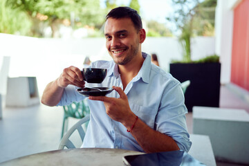 Young entrepreneur enjoying a cup of coffee at an outdoor cafe, taking a break from work