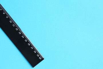 One black ruler on light blue background, top view. Space for text