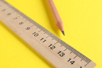 Ruler and pencil on yellow background, closeup