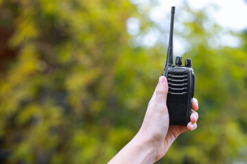Woman with walkie talkie outdoors, closeup. Space for text
