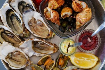 This beautiful seafood platter includes fresh oysters, clams, and mussels, elegantly arranged on ice. Served with zesty lemon wedges and tangy cocktail sauce, its a delightful feast.