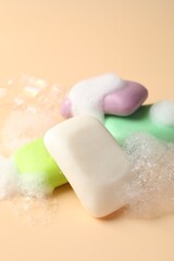 Soap bars with foam on beige background, closeup
